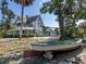 Historic home featuring a front porch with a green and white exterior, complemented by a vintage boat on the property at 673 Crane Prairie Way, Osprey, FL 34229