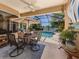 Covered outdoor patio and pool area with a table, chairs, umbrella and view of the lake at 673 Crane Prairie Way, Osprey, FL 34229