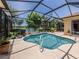 Inviting pool area featuring a sparkling pool, screen enclosure, and tropical landscaping with lake view at 673 Crane Prairie Way, Osprey, FL 34229