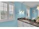 Bathroom with blue walls, shutters, granite countertops, and updated fixtures at 6731 Washington Pl, Bradenton, FL 34207