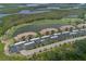 Aerial view of condo buildings, parking area, pond, and golf course showcasing the community layout at 7005 River Hammock Dr # 303, Bradenton, FL 34212
