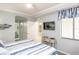 Bright bedroom featuring coastal decor, a mounted TV, and an adjacent bathroom at 7005 River Hammock Dr # 303, Bradenton, FL 34212