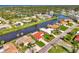Scenic aerial view of a waterfront home with a red tile roof, surrounded by lush landscaping and waterways at 74 Windsor Dr, Englewood, FL 34223