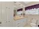 Bathroom with white cabinets, a large mirror, and natural lighting from the window at 74 Windsor Dr, Englewood, FL 34223