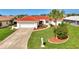 Charming single-story home featuring a red tile roof, a well-manicured lawn, and lush tropical landscaping at 74 Windsor Dr, Englewood, FL 34223
