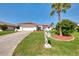 Charming home with a red tile roof and well-manicured lawn, complemented by tropical landscaping and a whimsical mailbox at 74 Windsor Dr, Englewood, FL 34223