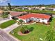 Charming house with a vibrant red tile roof, lush lawn, and colorful flowerbeds enhancing its curb appeal at 74 Windsor Dr, Englewood, FL 34223