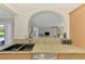View of the kitchen sink with granite countertops and an arched opening to the living room with a pool view at 74 Windsor Dr, Englewood, FL 34223