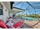 Screened-in in-ground pool area with furniture, a ceiling fan, and an umbrella for shade at 74 Windsor Dr, Englewood, FL 34223