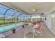 Screened-in patio with a dining set overlooking the in-ground pool and landscaping at 74 Windsor Dr, Englewood, FL 34223