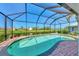 In-ground pool encased by a screen with brick pavers and a scenic backyard view at 74 Windsor Dr, Englewood, FL 34223