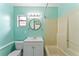 Bathroom boasts retro aqua walls, round mirror, vanity, and shower/tub combo at 8075 48Th N Ave, St Petersburg, FL 33709