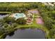 Aerial view of community amenities including a pool, playground, tennis courts, and a basketball court with a beautiful lake at 826 Honeyflower Loop, Bradenton, FL 34212