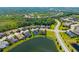 An aerial view of homes in a residential community surrounded by lush green trees and a lake at 826 Honeyflower Loop, Bradenton, FL 34212