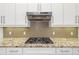 Close-up of a modern gas stovetop and decorative backsplash in a bright kitchen at 826 Honeyflower Loop, Bradenton, FL 34212