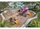 An aerial view of a community playground with slides, swings, and other play equipment; nearby a swimming pool at 826 Honeyflower Loop, Bradenton, FL 34212