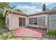 View of the rear of the house with a concrete patio, overgrown landscaping and boarded up windows at 9300 Gulf Blvd, St Pete Beach, FL 33706