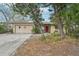 Modest exterior of single Gathering home featuring an attached garage and mature trees in the yard at 9300 Gulf Blvd, St Pete Beach, FL 33706