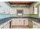 A vintage kitchen with worn cabinets and appliances featuring an open ceiling needing refurbishment at 9300 Gulf Blvd, St Pete Beach, FL 33706