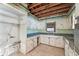 A vintage kitchen featuring worn cabinets, outdated appliances, and open ceiling, requiring refurbishment at 9300 Gulf Blvd, St Pete Beach, FL 33706