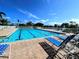 Community pool and brick lanai with blue lounge chairs on a sunny day at 967 Waterside Ln # 1, Bradenton, FL 34209