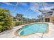 Clear blue pool surrounded by screened enclosure and view to home's exterior at 1026 Graham Rd, Venice, FL 34293