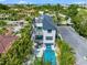 A modern white home with a pool, balconies, and a rooftop deck surrounded by lush greenery and tropical trees at 128 Fillmore Dr, Sarasota, FL 34236