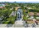 Aerial view of a modern three-story white home with a black roof surrounded by lush greenery and other houses at 128 Fillmore Dr, Sarasota, FL 34236