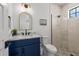 Stylish bathroom featuring a blue vanity, marble countertop, decorative mirror, and glass-enclosed shower at 128 Fillmore Dr, Sarasota, FL 34236