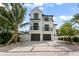Charming three-story white home with black trim, balconies, two-car garage, and palm tree in the front yard at 128 Fillmore Dr, Sarasota, FL 34236