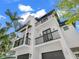A modern white three-story home with black trim, balconies, two-car garage, and tropical landscaping around the property at 128 Fillmore Dr, Sarasota, FL 34236