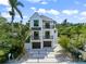 A modern white three-story home features black trim, balconies, a two-car garage, and a neatly landscaped front yard at 128 Fillmore Dr, Sarasota, FL 34236