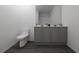 Well-lit modern bathroom with dual vanity, gray cabinets, and toilet on wood flooring at 13046 Bayberry Way, Parrish, FL 34219