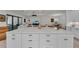 A detailed view of the white kitchen island with white countertop and black hardware in an open floorplan setting at 15315 Derna Ter, Bradenton, FL 34211