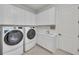 Functional laundry room with white cabinetry, modern washer and dryer, and a utility sink at 15315 Derna Ter, Bradenton, FL 34211
