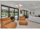 Bright living room with leather chairs, a white couch, and sliding glass doors to a patio and pool at 15315 Derna Ter, Bradenton, FL 34211