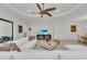 Open concept living room with a modern white sofa, ceiling fan, and a stylish entertainment center with a flat-screen TV at 15315 Derna Ter, Bradenton, FL 34211