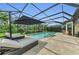 Pool area with lounge chairs and an umbrella, enclosed in a screened patio for outdoor living at 15315 Derna Ter, Bradenton, FL 34211