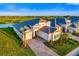 An aerial view of a stunning, modern home with tile roof, lush landscaping, and brick driveway near a serene lake at 17128 Ranchside Pl, Lakewood Ranch, FL 34211