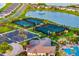 Overhead view of the tennis courts, adjacent to the community pool and clubhouse, surrounded by palm trees and landscaped grounds at 17128 Ranchside Pl, Lakewood Ranch, FL 34211