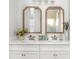 Bright bathroom featuring double sinks, sleek countertops, and decorative mirrors with wood trim at 17128 Ranchside Pl, Lakewood Ranch, FL 34211
