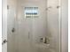 Modern bathroom shower with glass door, neutral tile, and small window at 17128 Ranchside Pl, Lakewood Ranch, FL 34211