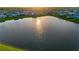 Aerial view of a community with a pond reflecting the bright sunshine at dusk at 17128 Ranchside Pl, Lakewood Ranch, FL 34211