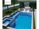 Modern pool with a jacuzzi, waterfall feature, and lounge area surrounded by palm trees and greenery at 17128 Ranchside Pl, Lakewood Ranch, FL 34211