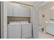 Functional laundry room with washer, dryer, and storage cabinets, leading to the bathroom at 2070 Crystal Lake Trl, Bradenton, FL 34211