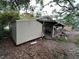 View of the backyard with a shed, partially covered porch, and overgrown vegetation at 2230 50Th N Ave, St Petersburg, FL 33714