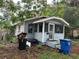A quaint, light blue single-story home with a covered porch and a yard strewn with debris and garbage at 2230 50Th N Ave, St Petersburg, FL 33714
