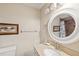 Neutral toned bathroom featuring a round mirror over the sink and tan countertop at 2639 Woodgate Ln # H8, Sarasota, FL 34231