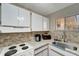 Kitchen with white cabinets, granite countertops, tiled backsplash, and a stainless steel sink at 2763 Woodgate Ln # 211, Sarasota, FL 34231