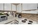 Functional kitchen boasts granite counters, white cabinets, and tiled backsplash at 2763 Woodgate Ln # 211, Sarasota, FL 34231